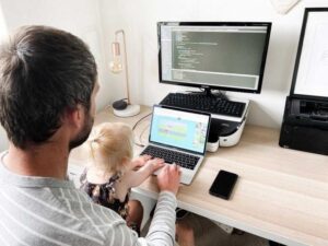 Vuxen och barn vid en laptop med kod på en extern skärm