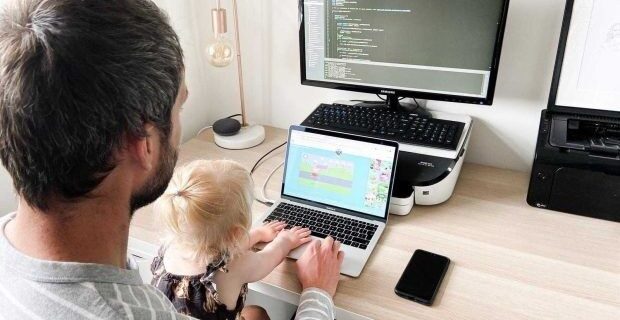 Vuxen och barn vid en laptop med kod på en extern skärm