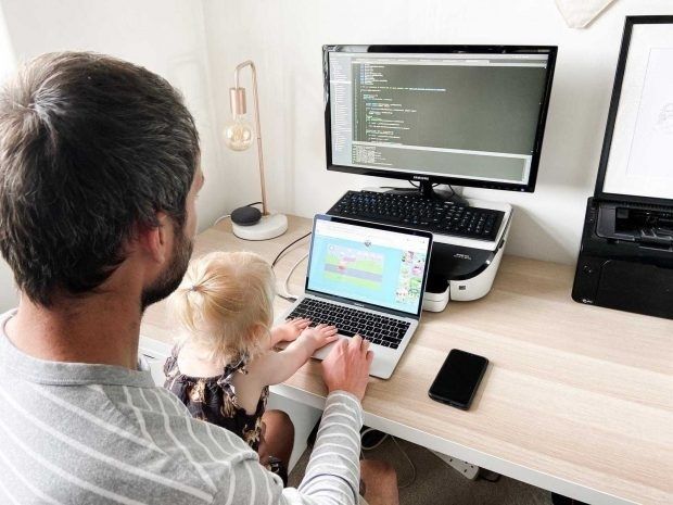 Vuxen och barn vid en laptop med kod på en extern skärm